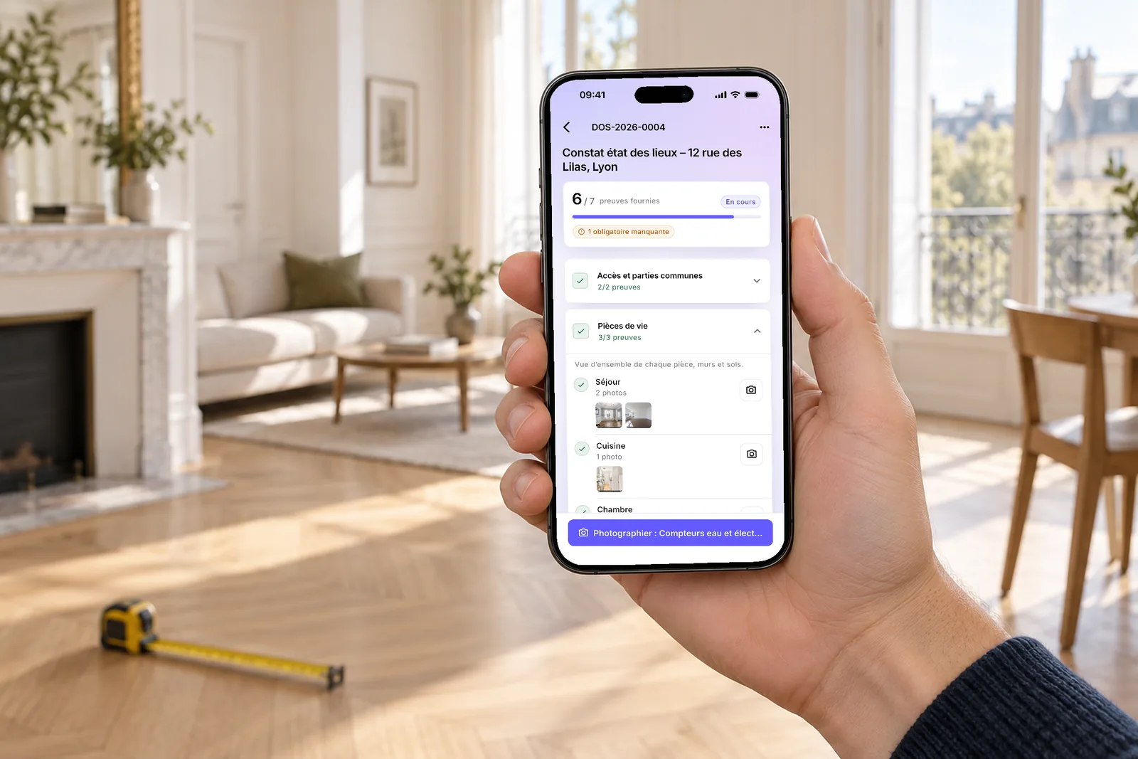 Une main tient un téléphone qui affiche un état des lieux en cours dans l’application Givre