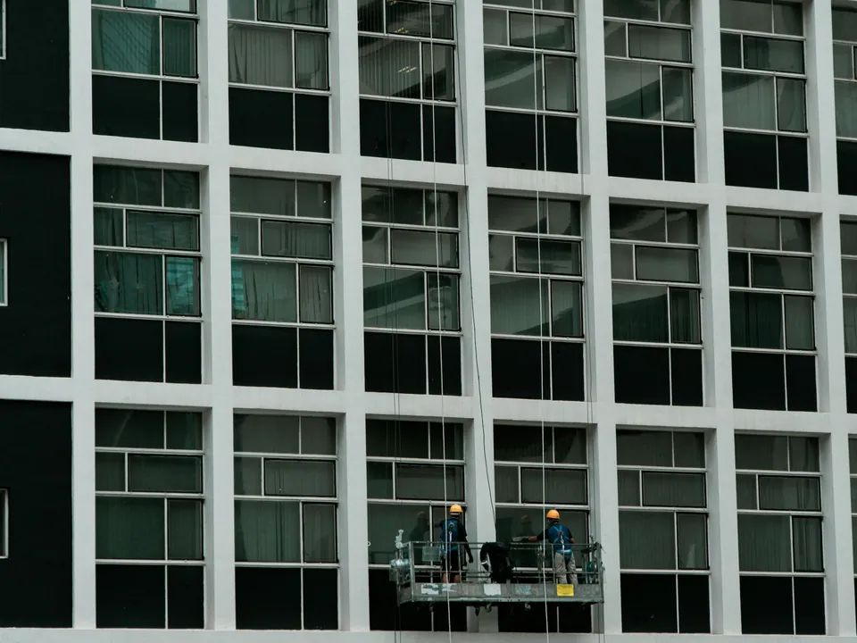 Deux techniciens sur une nacelle devant une façade vitrée