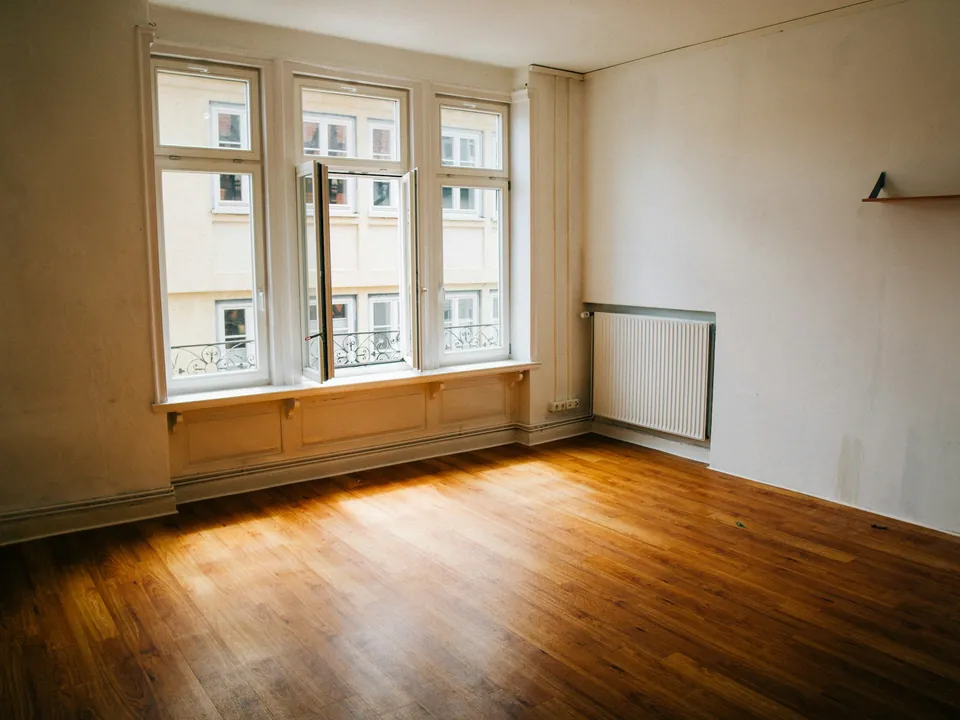 Une chambre vide avec parquet et grande fenêtre